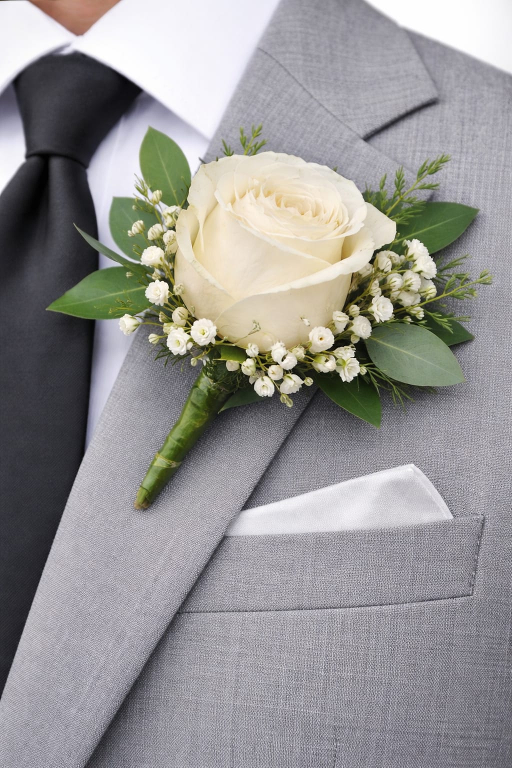 White rose boutonniere pinned to a gray suit jacket