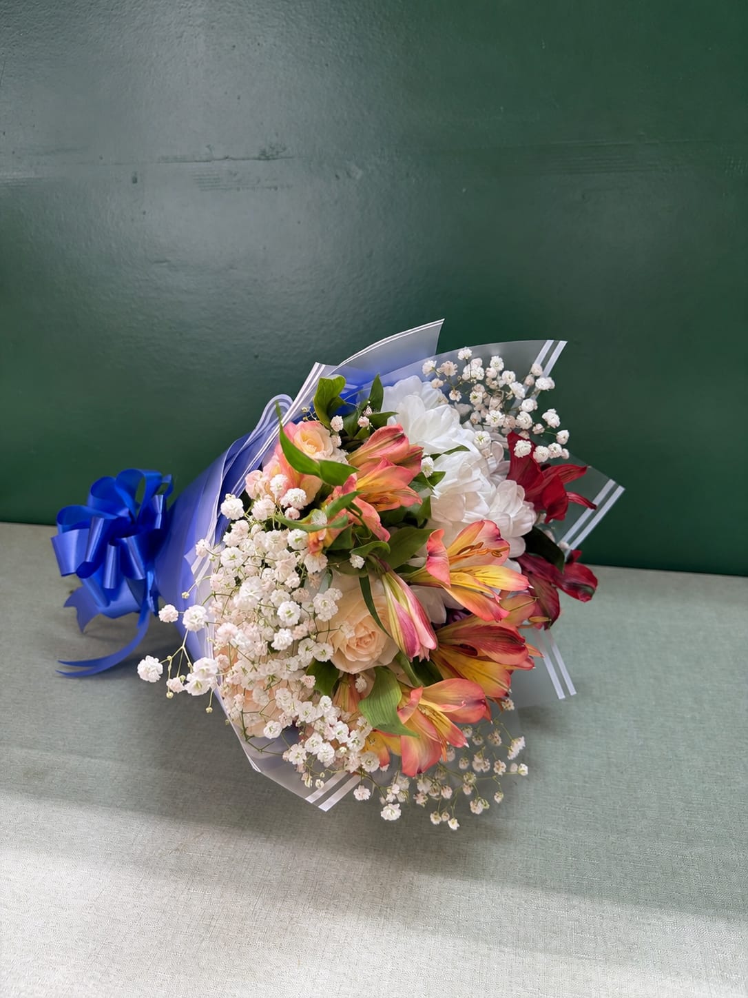 Bouquet of pink and white flowers wrapped in blue paper with a ribbon