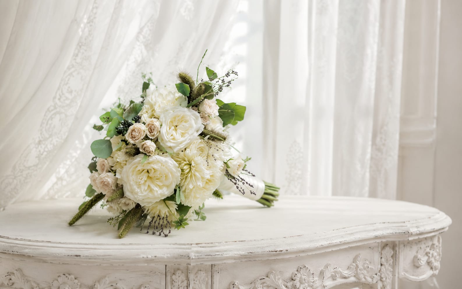 Yes please  - A soft, garden-inspired bridal bouquet that reads as timeless romance-perfect as wedding flowers or for a formal celebration. The rounded, hand-tied shape and pale palette of white, cream, and blush make this bouquet an elegant choice for the person you're honoring on their wedding day or for a bridesmaid who should feel quietly celebrated.  This arrangement features classic roses and daisies with other delicate blooms in white and green tones, punctuated by small blush roses that add a warm, romantic note. The gathered, slightly loose texture gives it an airy, natural look, and the stems are finished with a neat bouquet wrap for comfortable carrying. Its refined, classic styling pairs well with both traditional and garden-themed weddings.  Made to make the recipient feel truly seen, this bouquet works beautifully for the bride who prefers understated elegance or as a meaningful gift for someone joining a formal occasion. Order details and sizing are available at checkout; bouquets are hand-tied to preserve the fresh, airy silhouette and include simple care guidance to keep blooms looking their best through the day.   If any design elements are of major importance to your order, please include them in the florist instructions at checkout or contact us to ensure availability.