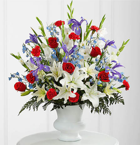 FTD Cherished Farewell™ Arrangement - The Cherished Farewell™ Arrangement is an elegant display of patriotic beauty to honor your loved one at their final farewell service. Red roses, red carnations, white gladiolus, light blue delphinium, blue iris, white Oriental lilies, white Asiatic lilies and lush greens are elegantly arranged in a white plastic urn to create a stunning way to say your last goodbye. 