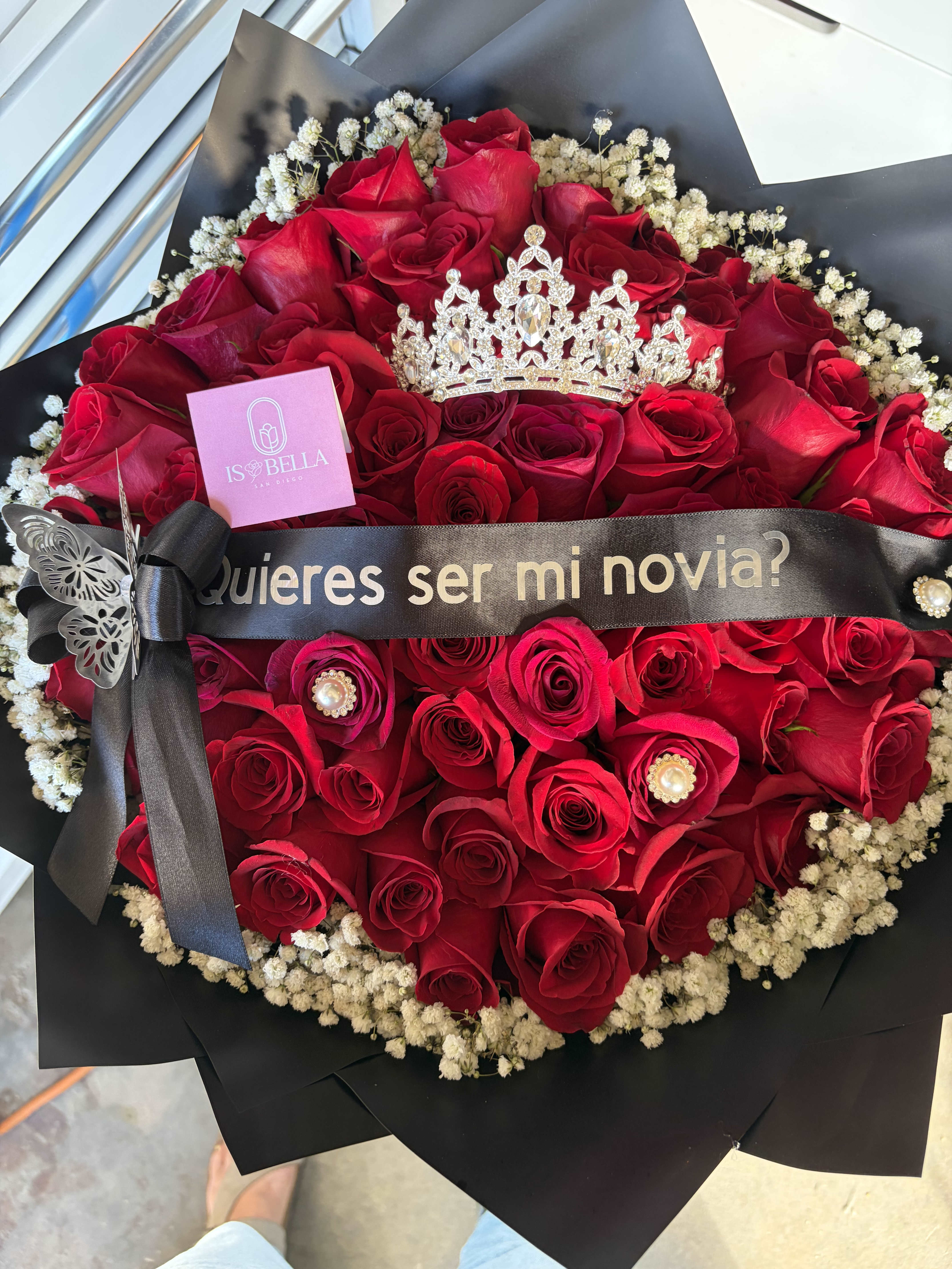 Red rose bouquet with baby's breath, black wrap, and a decorative crown