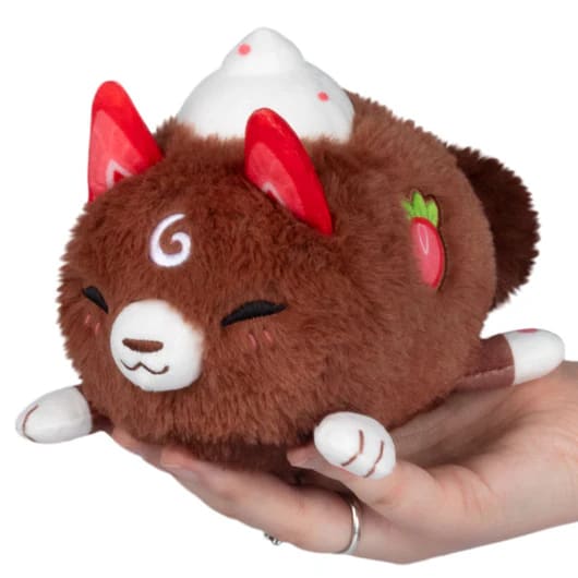Brown plush cat toy with red ears and white accents held in a hand