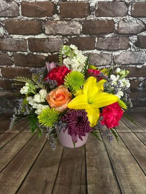 Mixed bouquet in a pink vase with a yellow lily and colorful blooms