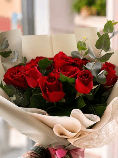Classic Red Rose Bouquet - Twelve velvety red roses with lush eucalyptus, wrapped in elegant cream paper and tied with a soft pink ribbon. Timeless, classic, and deeply romantic — the perfect expression of love for any occasion.