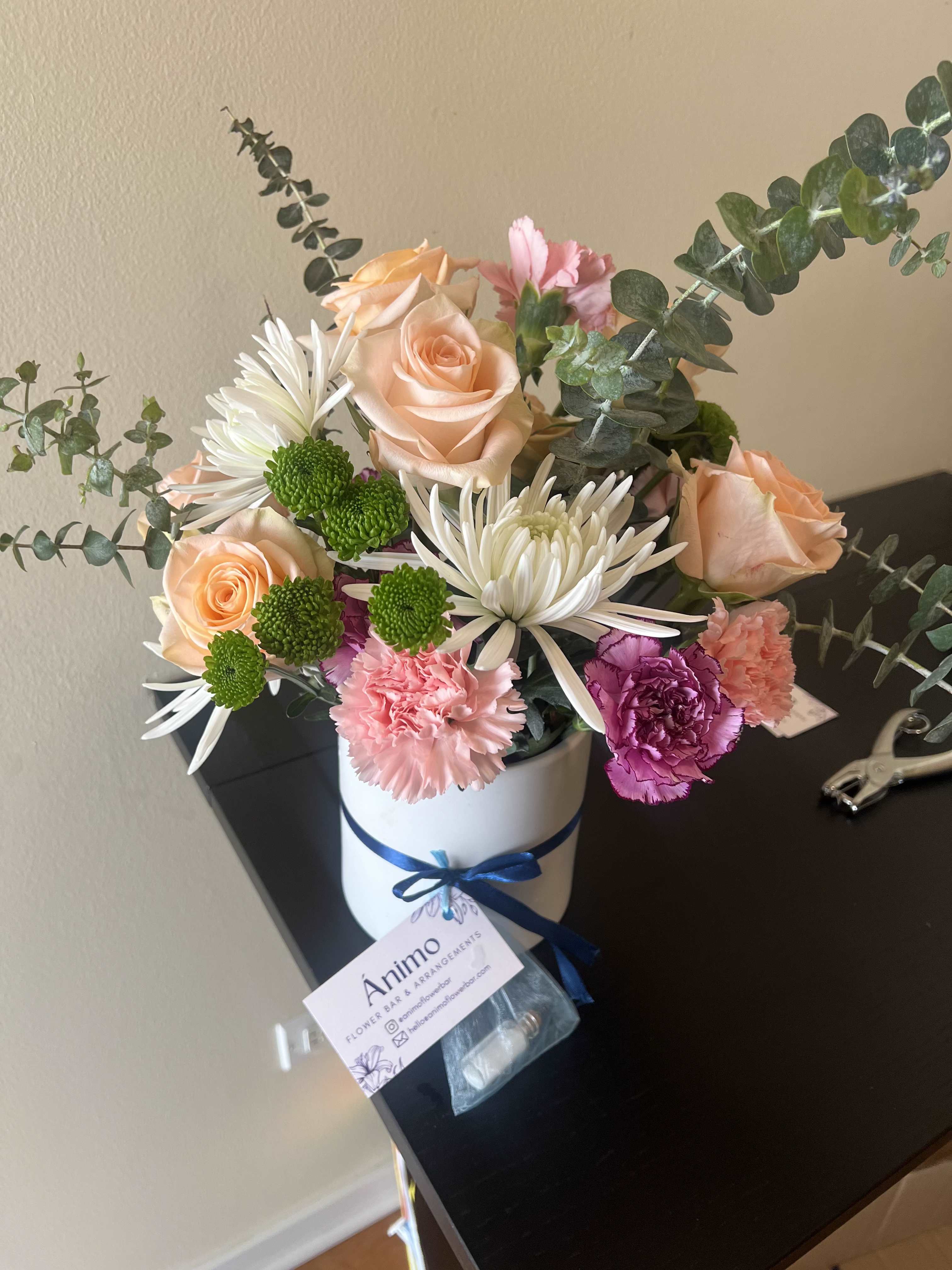 Velvet Romance Arrangement - Classic, passionate, and effortlessly chic — the Velvet Romance bouquet is a timeless declaration of love and admiration. Pink roses command attention at the heart of the arrangement, beautifully offset by soft white blooms, ruffled carnations.   Hand-tied and place in an elegant vase. This arrangement is as stunning in person as it is in photos — a gift that speaks volumes without saying a word.