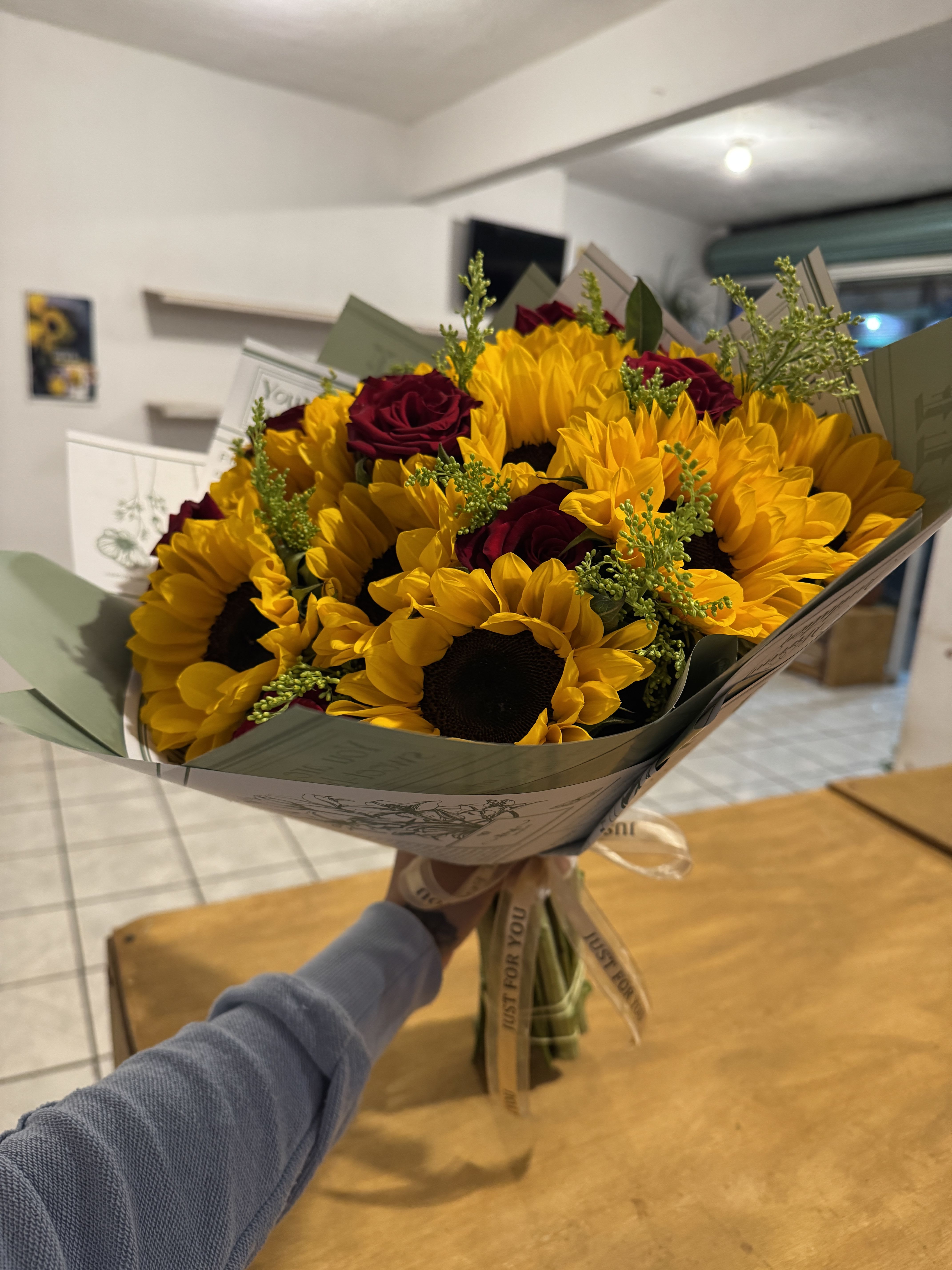 Sunflower &amp; Red Rose Bouquet - A bold, generous bouquet of large sunflowers and deep red roses with solidago filler, wrapped in illustrated paper and finished with a ribbon. Bright, warm, and impossible to ignore — perfect for celebrations and congratulations.
