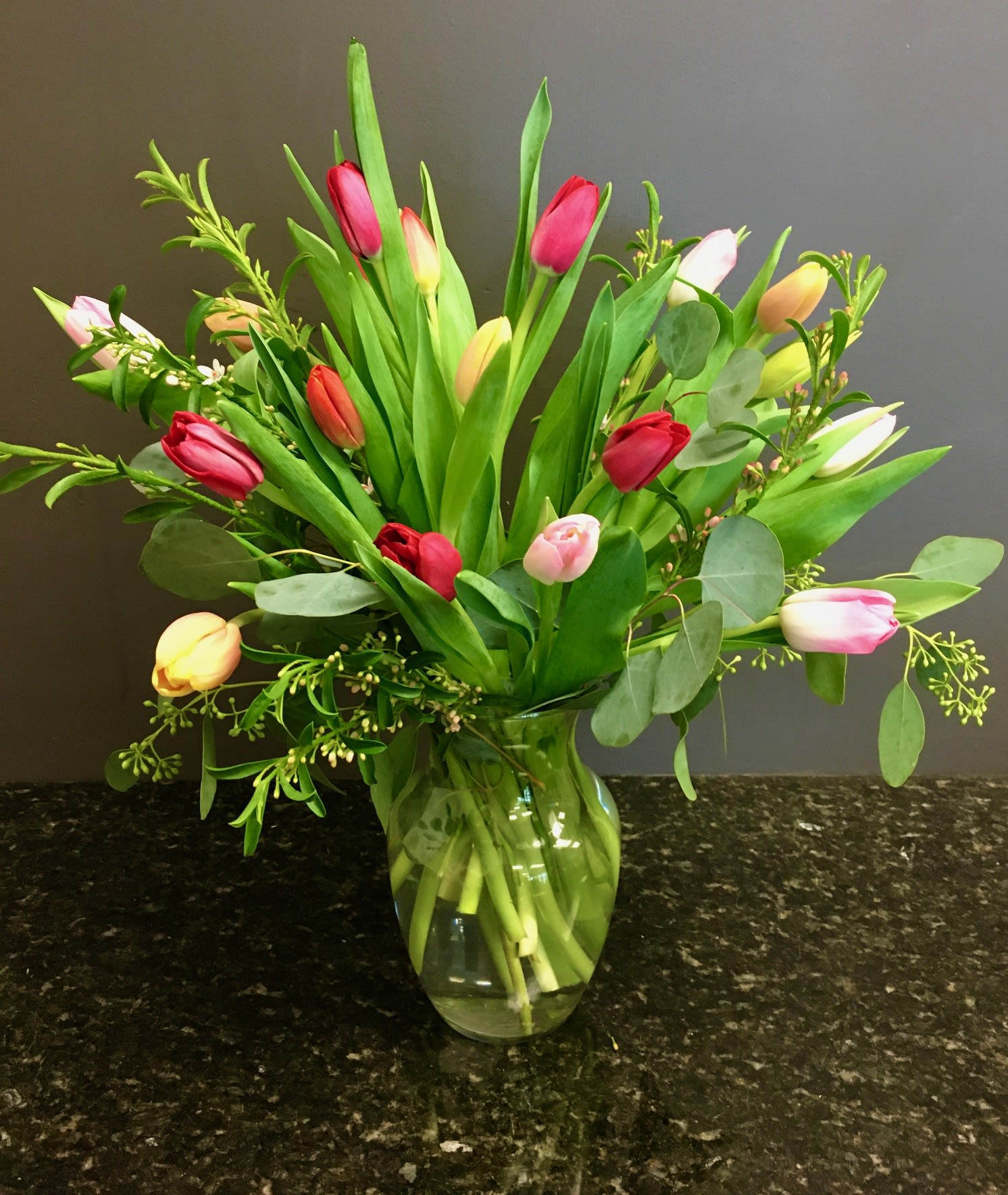 Bouquet of multicolored tulips in a clear glass vase