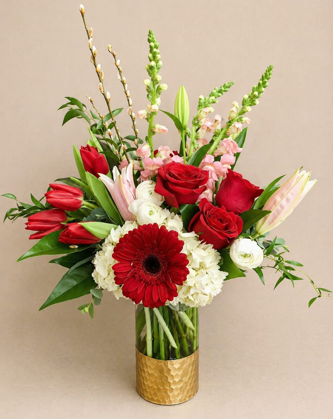 Red roses, tulips, and a gerbera daisy in a gold vase