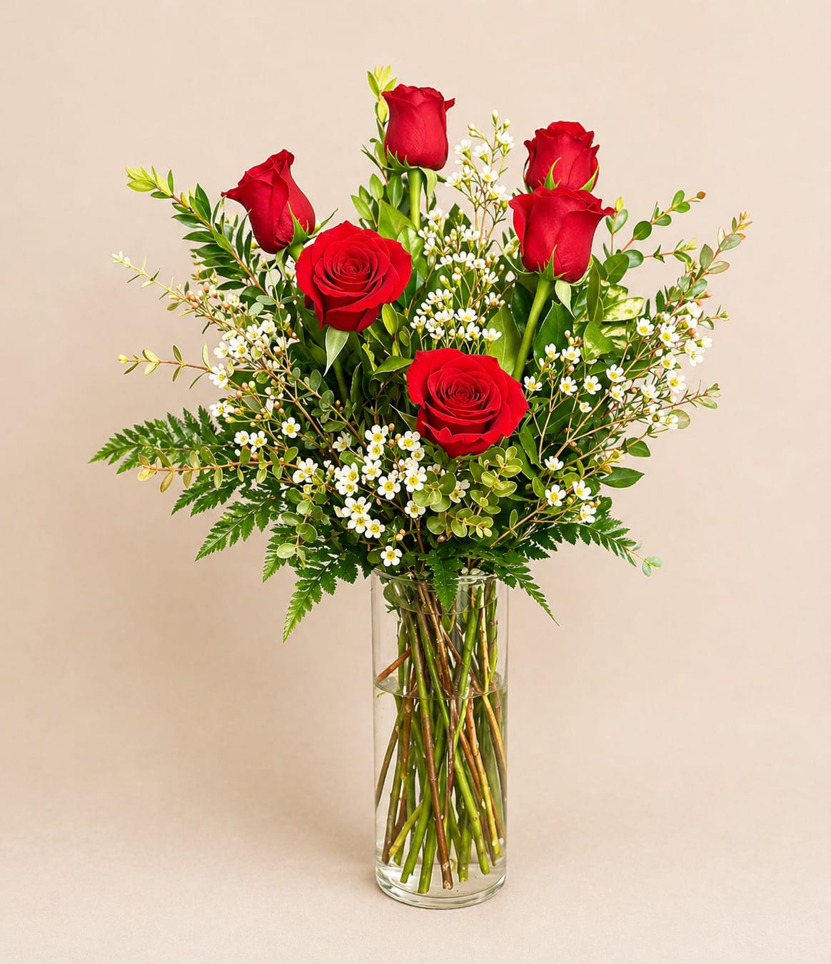 Red roses and white filler flowers in a clear glass vase