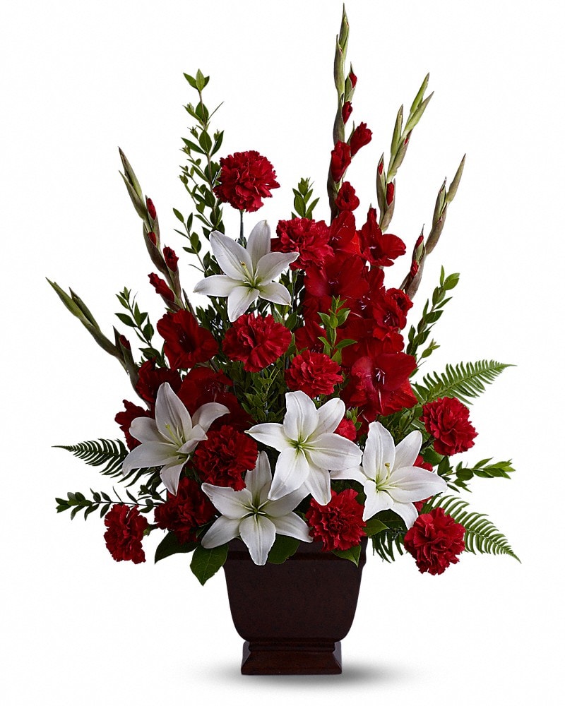 Teleflora's Tender Tribute - Vivid and touching, vibrant reds and serene whites blend in honor and celebration of a life filled with love, light and grace. Beautiful fresh flowers such as red gladioli and carnations with white asiatic lilies set amidst myrtle, sword fern, and salal in an exclusive Noble Heritage Urn.