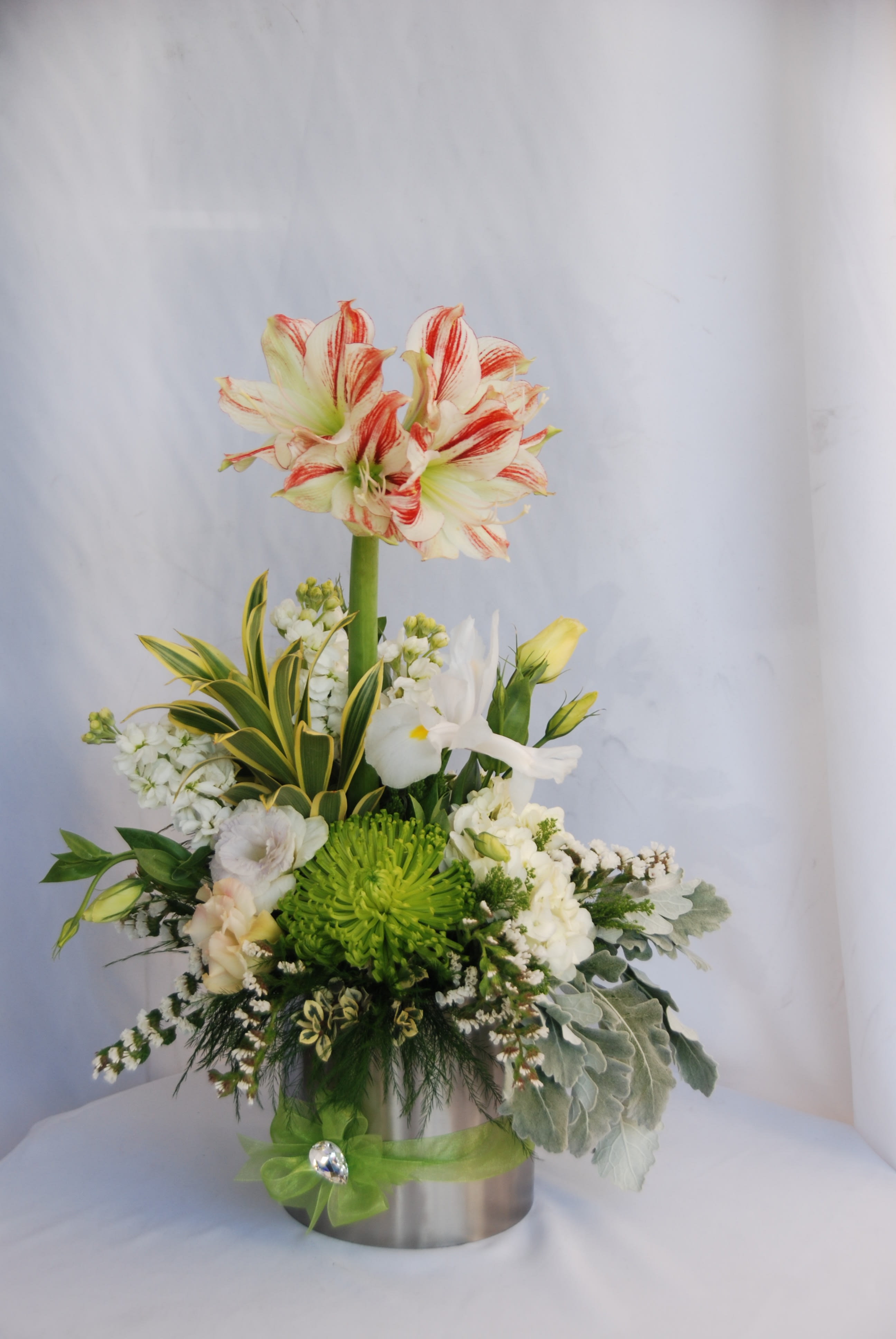 Tall floral arrangement with red-striped white lilies in a metal vase