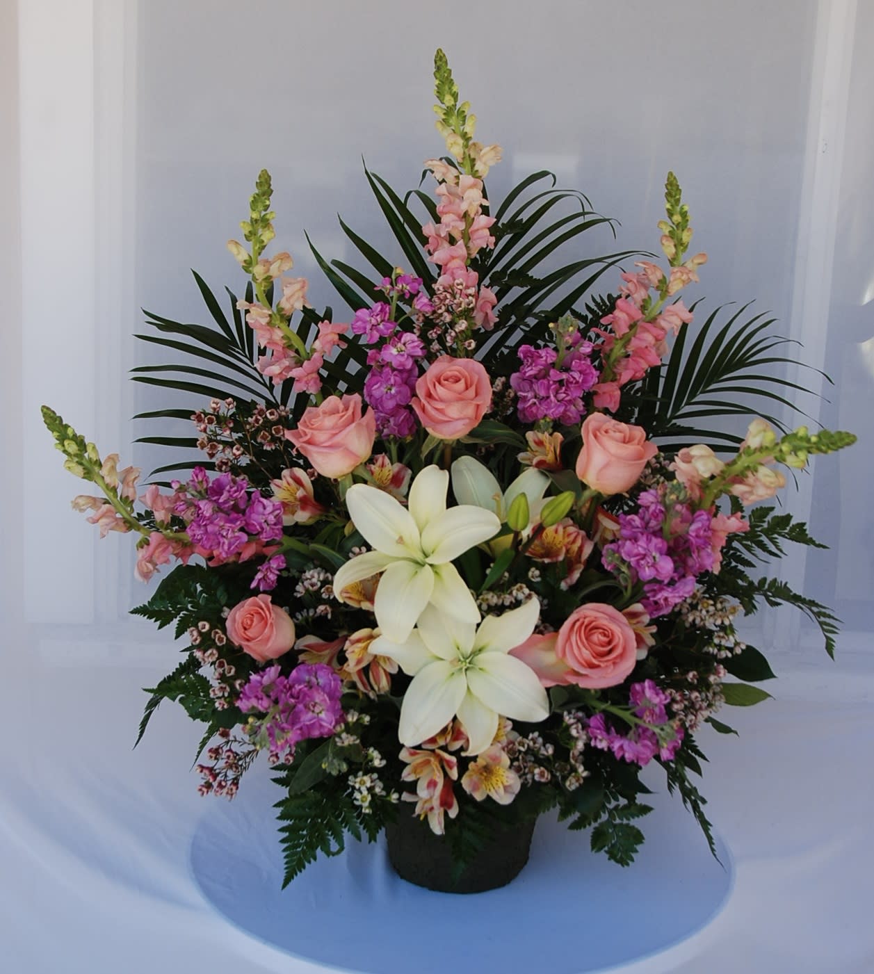 In Loving Memory  - A traditional pastel arrangement of snapdragons, stocks, roses, astromelias, and lilies.
