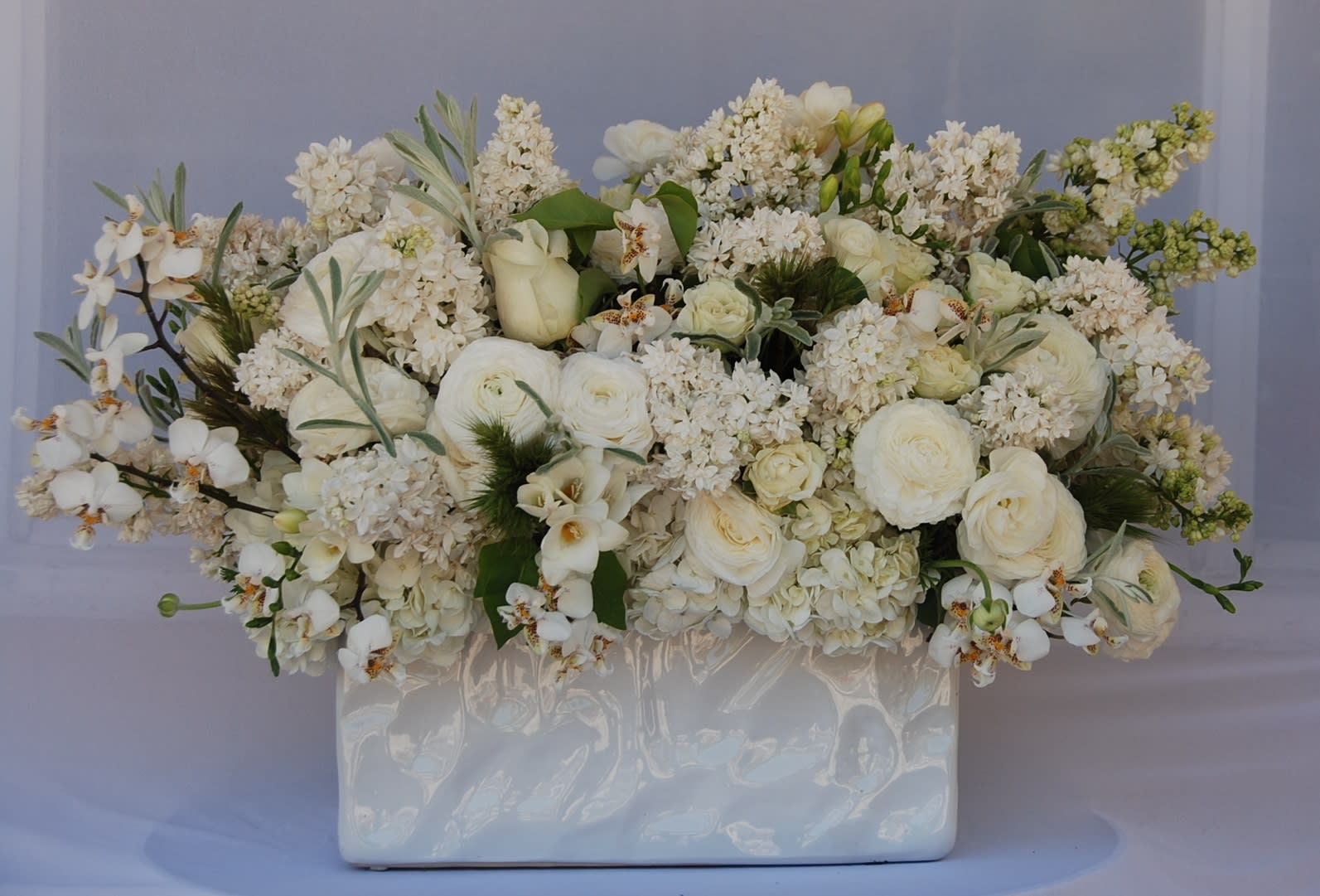 White floral arrangement in a glossy rectangular vase