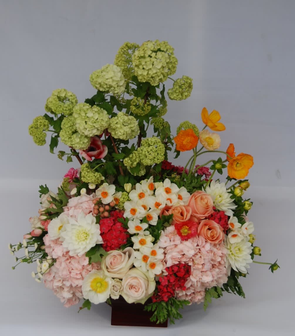Large mixed floral arrangement with pale green blooms, pink roses, and white flowers