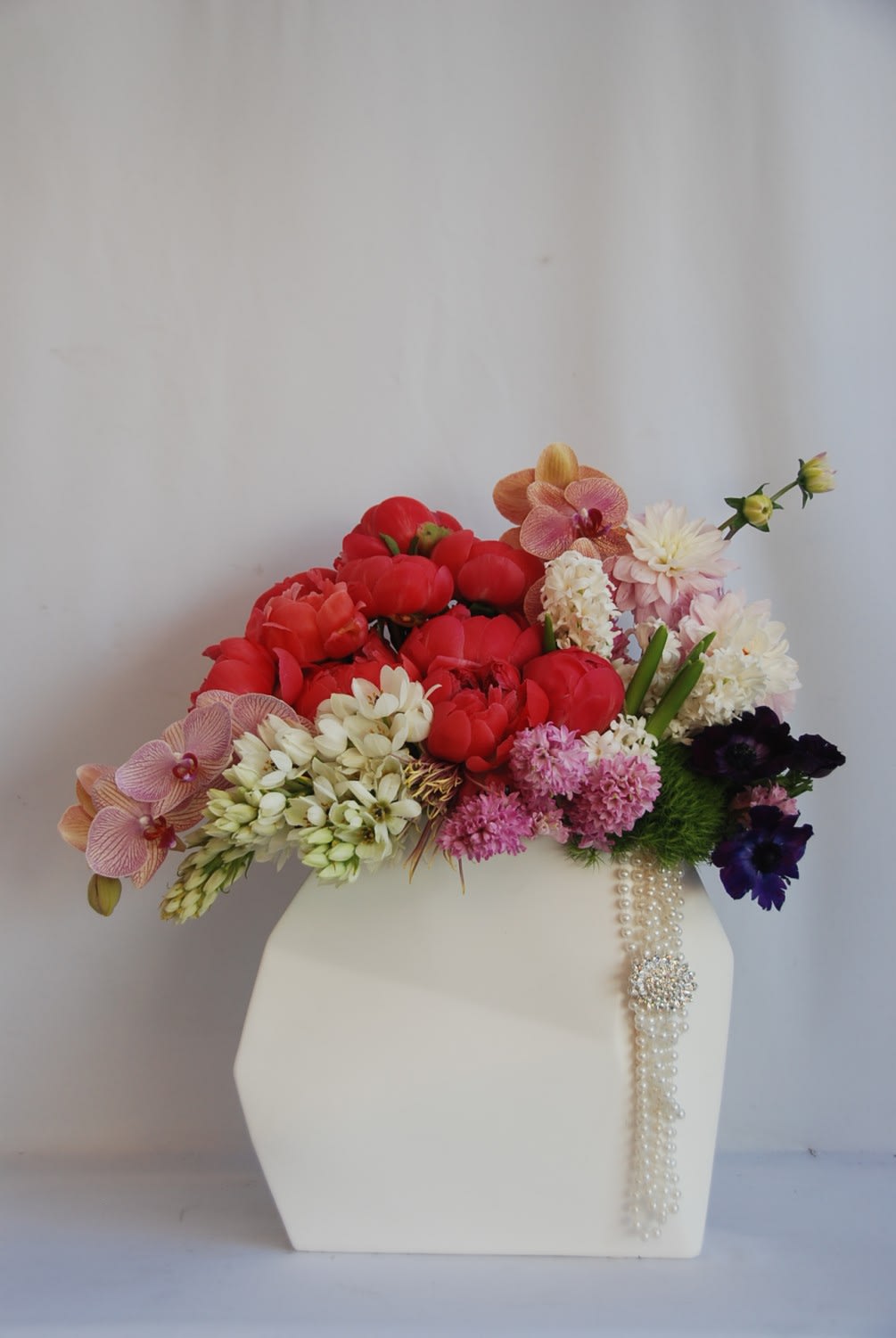 Arcardia CA Flowers - An elegant arrangement of coral peonies, dahlias, hyacinths, phalaenopsis orchids, star of bethlehem and anemones in a white ceramic container. 