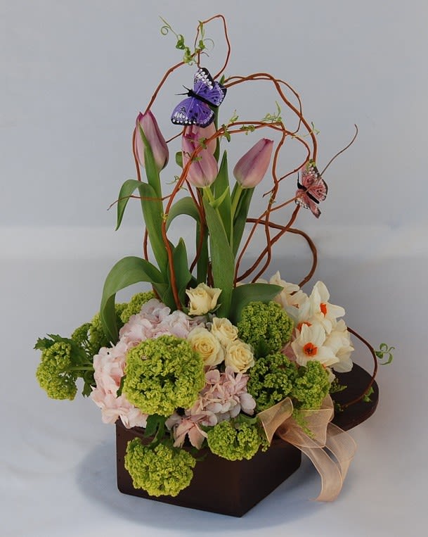 Pink tulips and mixed flowers in a dark box with decorative butterfly picks