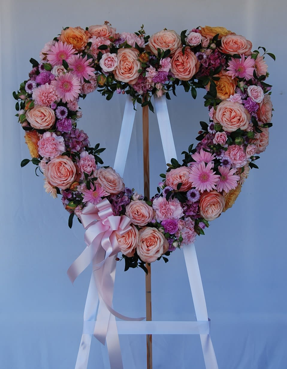 Sweetheart - An open heart sympathy arrangement filled with pink chrysanthemums. A side accent spray with pink carnations, and garden roses.