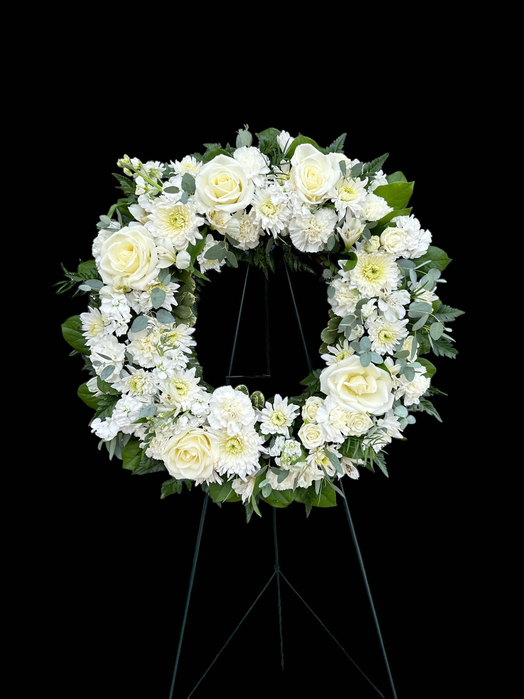 White floral wreath on a black easel stand
