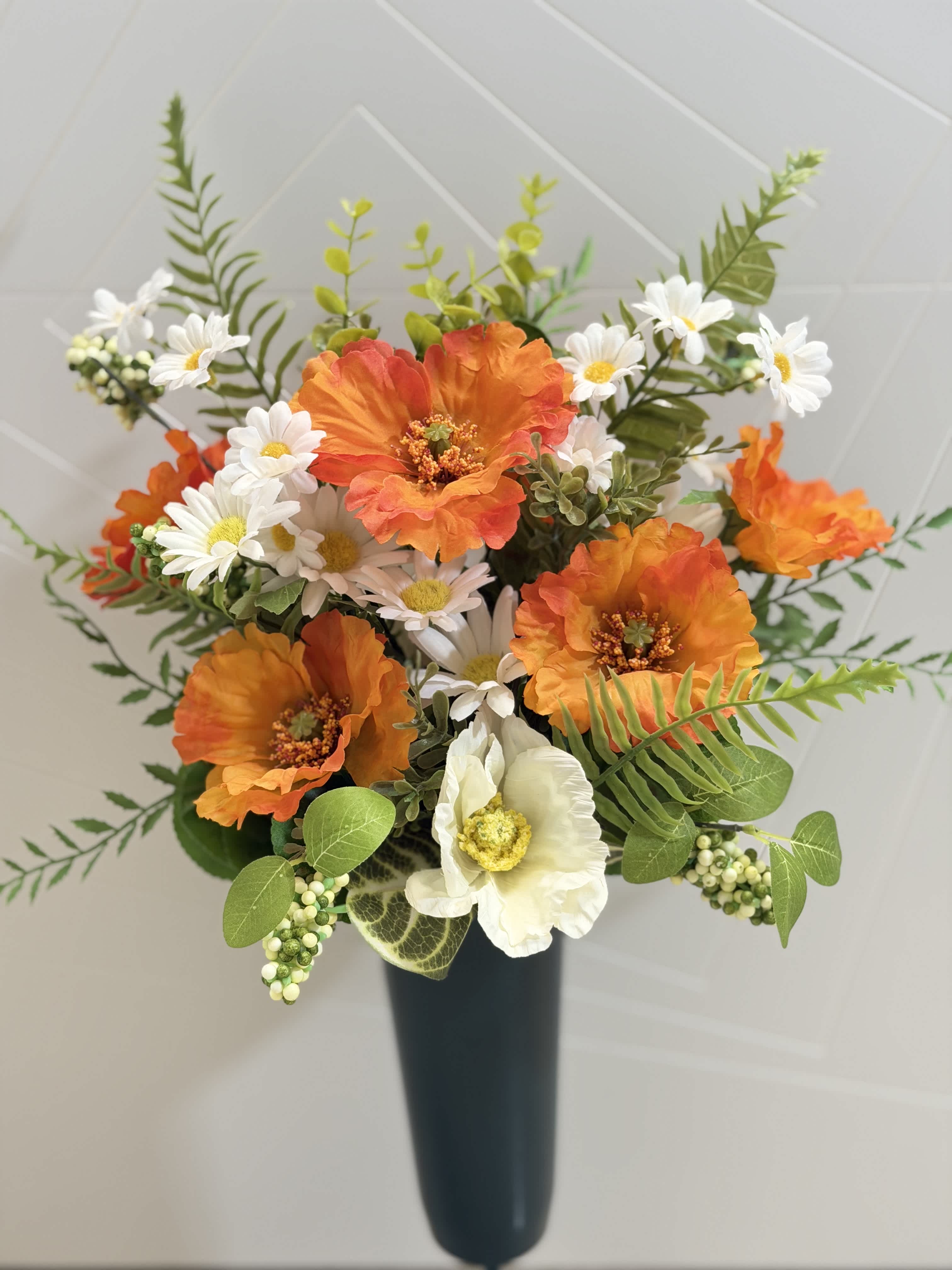 Orange and white flowers arranged in a tall black vase