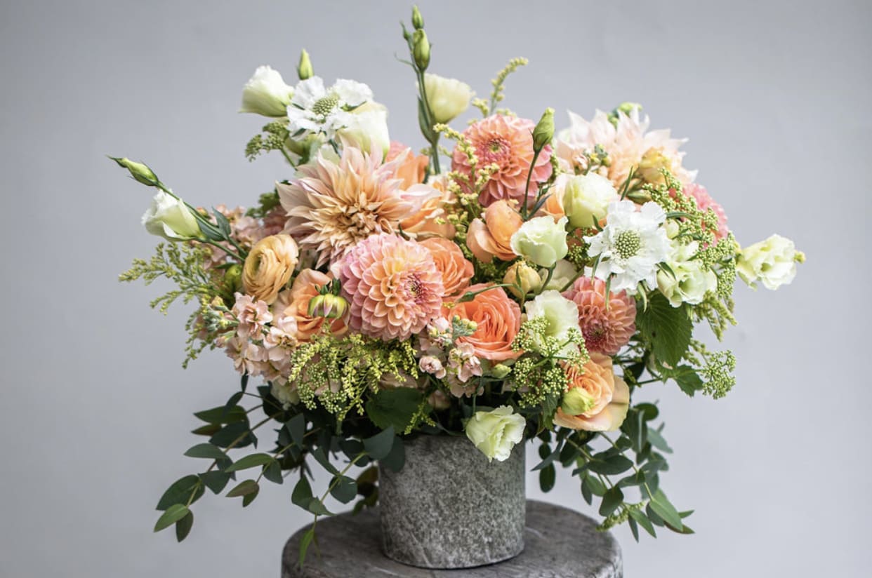 Peach and white mixed flower arrangement in a gray vase