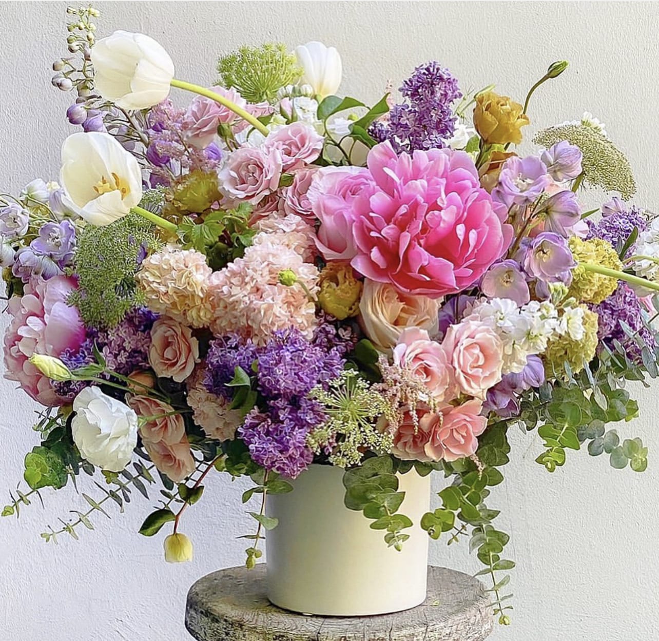 Mixed bouquet of pink, purple, and white flowers in a white vase