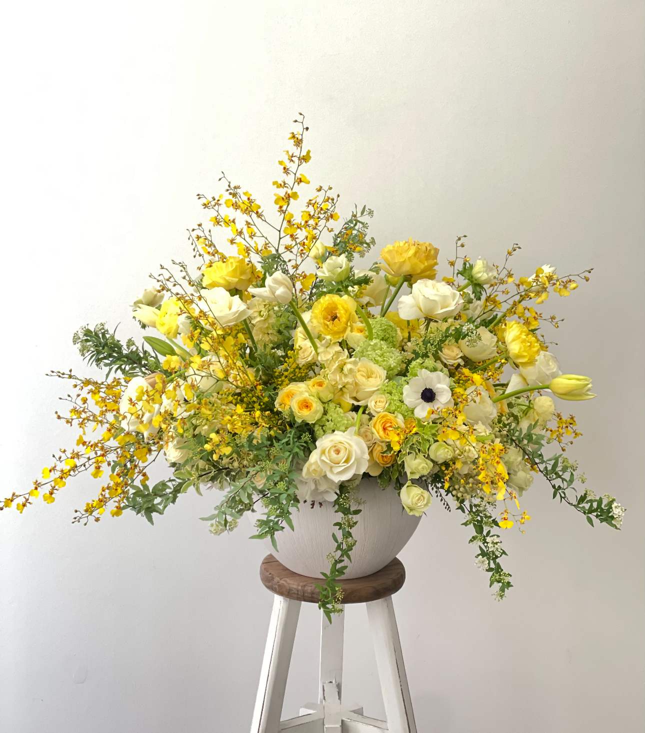 Large yellow and white floral arrangement in a white vase