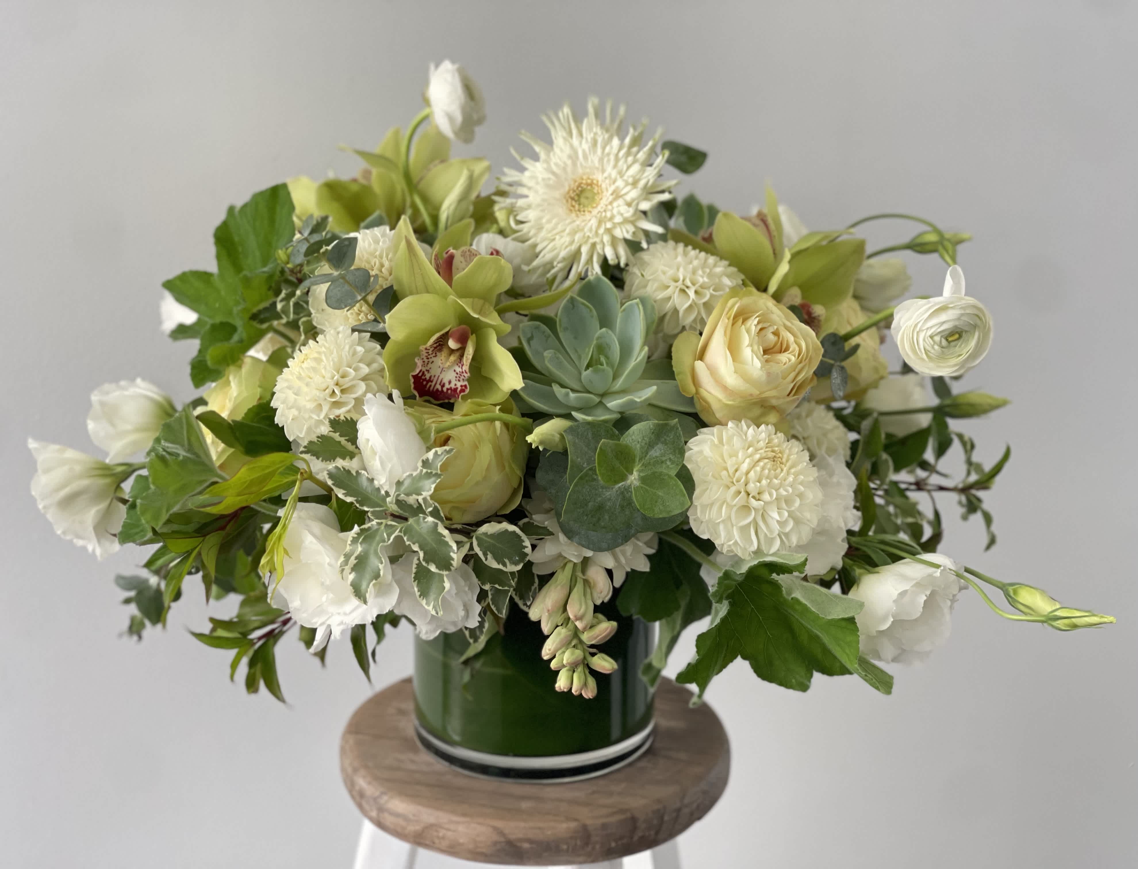 White and pale green floral arrangement in a green glass vase