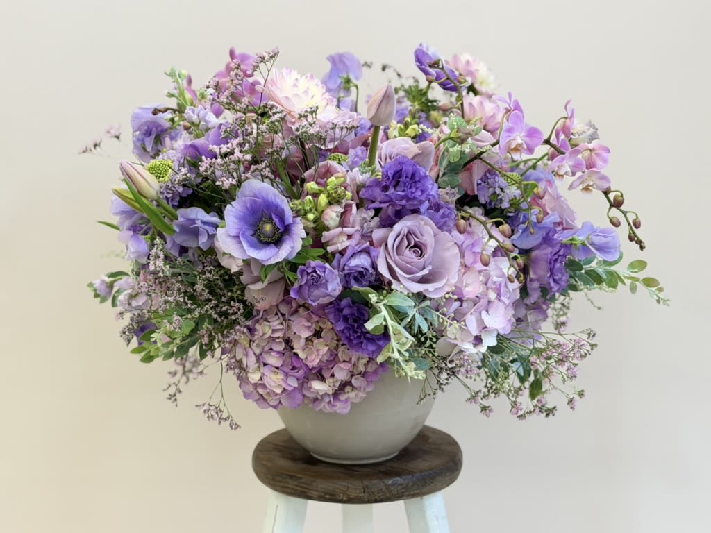 Lavender and purple floral arrangement in a white vase