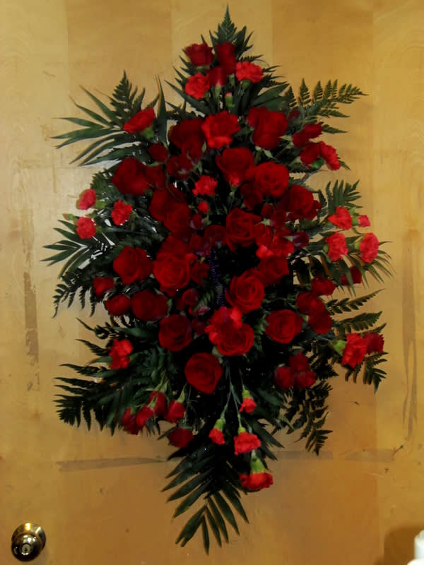 Large red rose and carnation spray with dark greenery