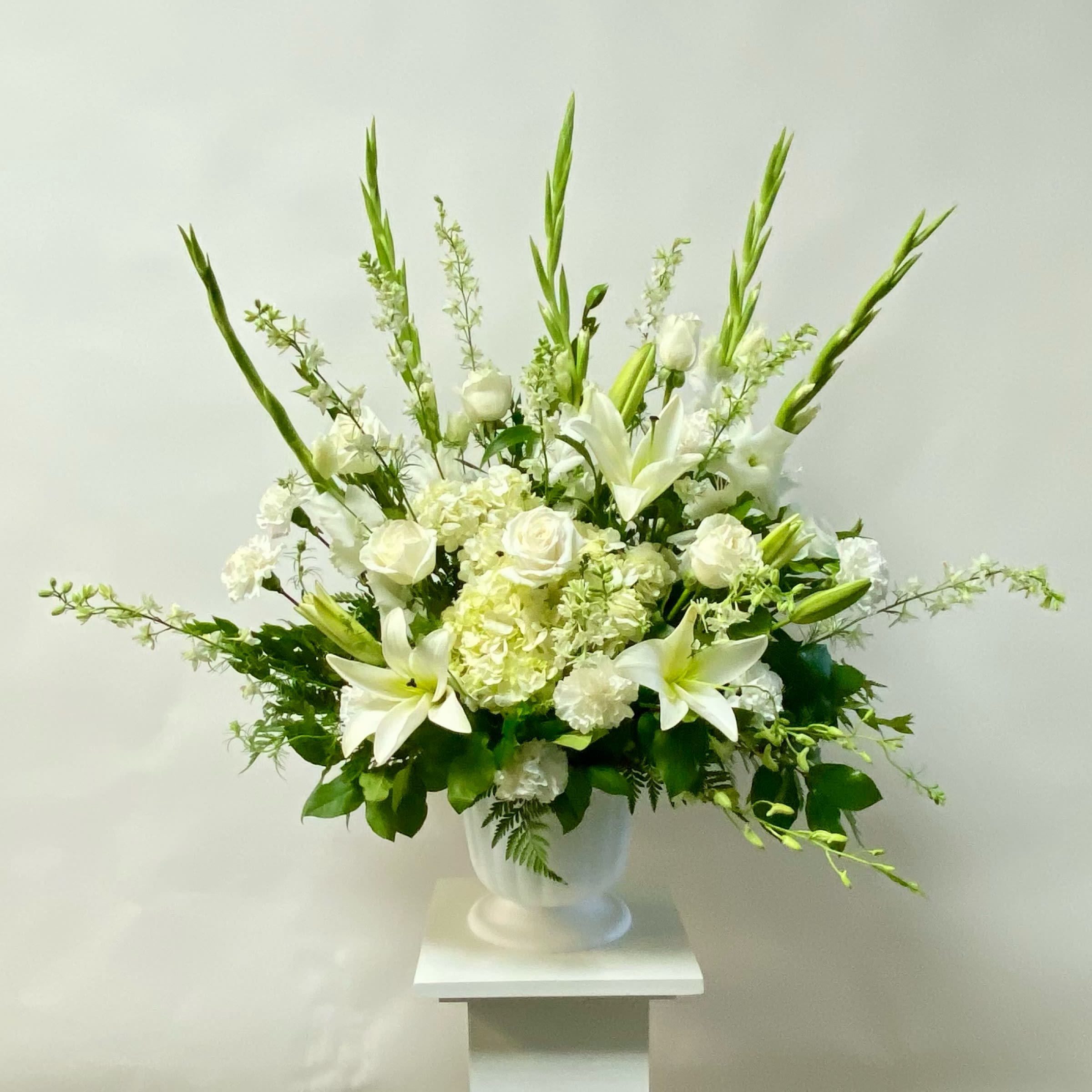 White floral arrangement in a white urn vase