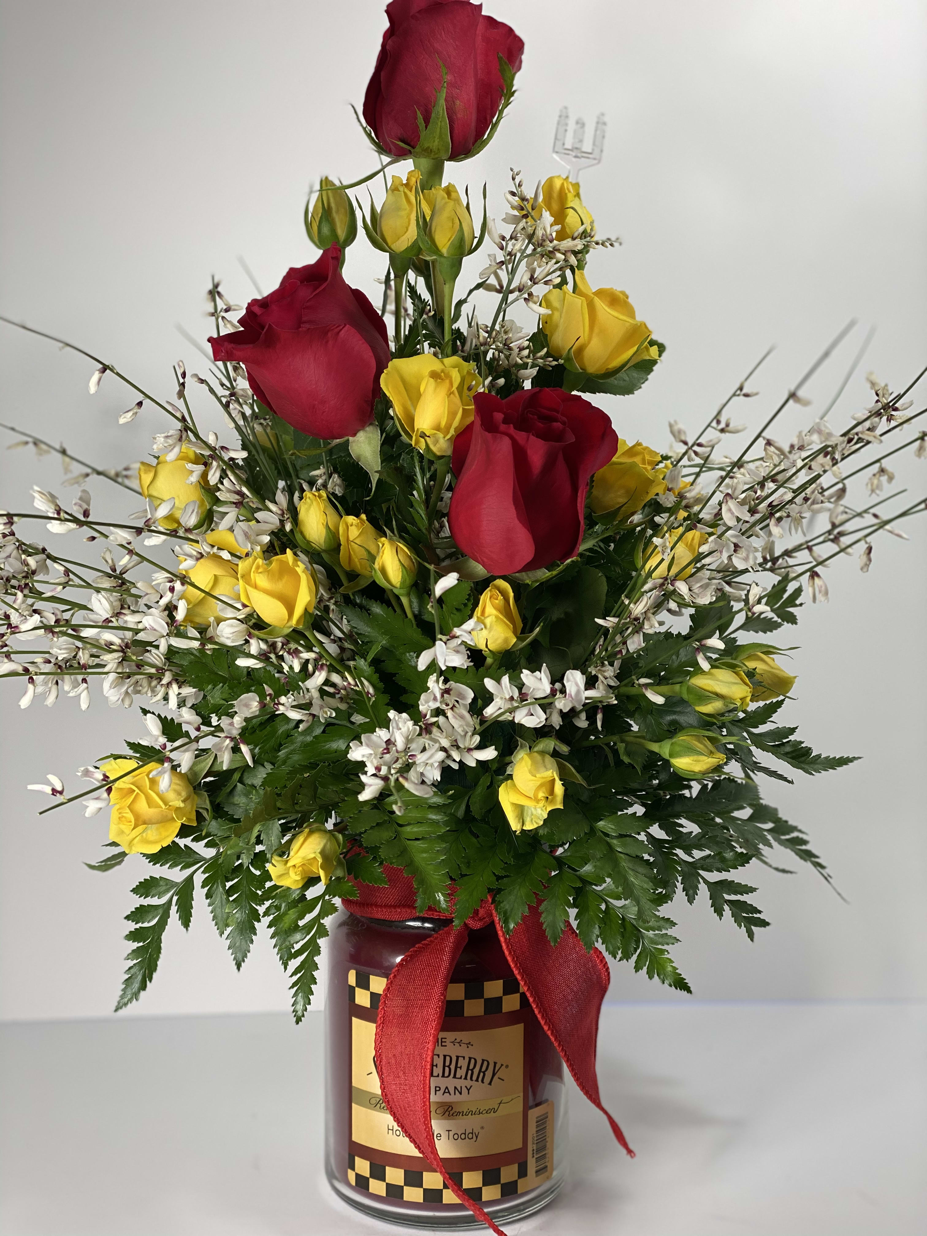 Red and yellow roses in a glass jar with a red ribbon