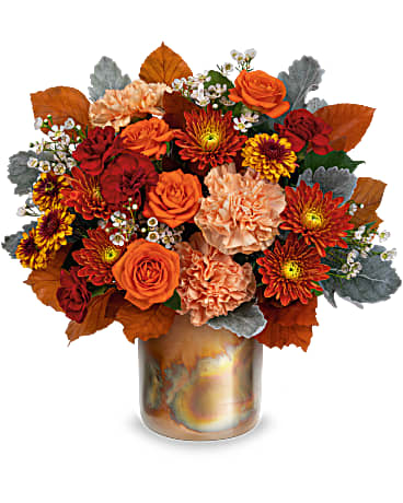  Blooming Beauty Bouquet - Take a shine to fall décor with this shimmering, copper-hued metal keepsake bursting with beautiful autumnal flowers. This autumn arrangement has orange spray roses, peach carnations, miniature maroon carnations, bronze button spray chrysanthemums, bronze cushion spray chrysanthemums and white wax flower accented with dusty miller and brown copper beech. This Blooming Beauty Bouquet is delivered in Teleflora's Harvest Blooms Cylinder. Approximately 13 1/4" W x 12 3/4" H 