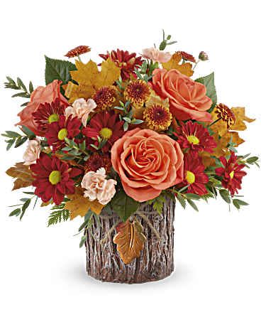 Enchanted Forest Bouquet - Capture their admiration with this enchanting fall rose arrangement, elegantly complemented by a vase inspired by tree bark and a ceramic autumn leaf charm. Teleflora's Enchanted Forest Bouquet features vibrant orange roses, delicate peach miniature carnations, bronze button spray chrysanthemums, bronze daisy spray chrysanthemums, parvifolia eucalyptus, and lush leatherleaf fern. Presented in Teleflora's Enchanted Forest Cylinder, it exudes natural charm and elegance with warm tones. Approximately 13 1/2" W x 12 1/2" H