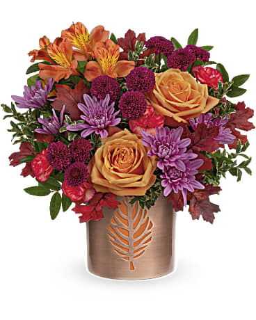 Autumn Abloom Bouquet - Autumn comes to life in Teleflora's Autumn Abloom Bouquet that is artfully arranged in a fall-fabulous keepsake vase of copper-finished metal with delicate leaf cutout. This fall bouquet features light orange roses, orange alstroemeria, miniature orange carnations, purple cushion spray chrysanthemums, purple button spray chrysanthemums, huckleberry and oregonia. This fall bouquet is delivered in Teleflora's Lovely Leaves Cylinder. Approximately 12 1/2" W x 12 1/2" H