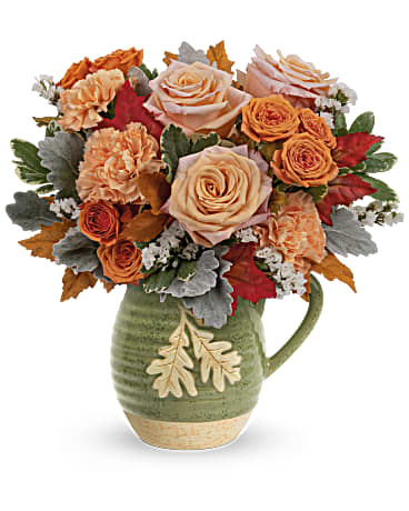 Rosy Autumn Bouquet - Rosy Autumn Bouquet is presented in a food- safe, glazed stoneware pitcher filled with fall flowers such as roses, carnations, and sinuata statice. This fall arrangement is sure to bring a rosy outlook to your loved one's life. Peach roses, orange spray roses, orange carnations and white sinuata statice are arranged with dusty miller and variegated pittosporum. Delivered in Teleflora's Charming Acorn Pitcher. Approximately 13" W x 13 1/4" H
