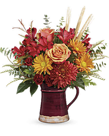 Fields Of Fall Bouquet Pitcher - Celebrate the harvest season with the hearth-inspired hues of this lush autumnal bouquet, hand-arranged in a glazed, food-safe ceramic pitcher. Lovely as a vase or for serving your favorite fall drinks! Light orange roses, red alstroemeria, miniature maroon carnations, bronze disbud chrysanthemums, and bronze daisy spray chrysanthemums are arranged with grevillea, spiral eucalyptus, and natural wheat. Delivered a  Fields of Fall Pitcher. Orientation: All-Around VASE: This beautiful fall pitcher is both charming and useful, guaranteed to be a treasured décor piece for years to come. FDA-approved to safely serve and store food and available exclusively from Teleflora. SIZE: 15" H X 16" W