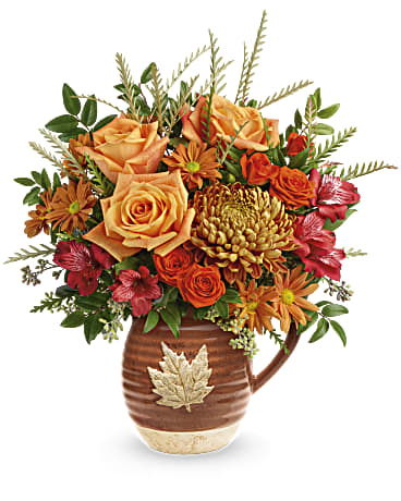 Cascading Blooms Bouquet - Capture the beauty of cascading fall leaves with this heartwarming rose bouquet in a gorgeous, glazed ceramic pitcher that's food safe for serving. Perfect to decorate your table for Thanksgiving or any special occasion. This autumn-inspired arrangement has orange roses, orange spray roses, red alstroemeria, orange daisy spray chrysanthemums and bronze disbud chrysanthemums arranged with seeded eucalyptus, huckleberry and grevillea. This Cascading Blooms Bouquet is delivered in Teleflora's Cascading Blooms Pitcher. Approximately 16" W x 18" H 