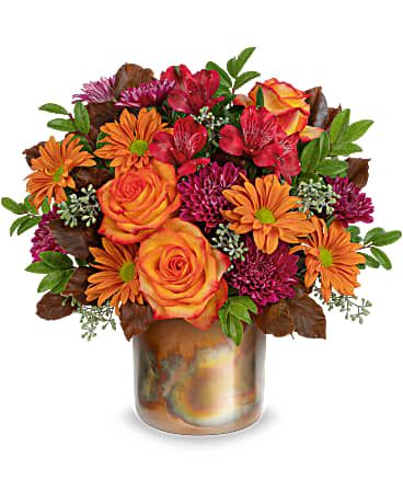 Harvest Blooms Bouquet - Make fall shimmer with this glorious autumnal rose bouquet, arranged in a breathtaking metal vase with unique copper patina. Orange bi-color roses, red alstroemeria, purple cushion spray chrysanthemums, bronze daisy spray chrysanthemums and brown copper beech are arranged with seeded eucalyptus and huckleberry. Delivered in Teleflora's Harvest Blooms Cylinder. Approximately 14" W x 13" H