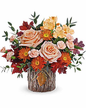Woodland Garden Bouquet - With its unique tree bark-inspired design, this magnificent vase featuring an autumnal rose bouquet is sure to become a favorite in fall décor. Telelfora's Woodland Garden Bouquet features soft peach roses, peach alstroemeria, and miniature peach carnations, complemented by bronze cushion spray chrysanthemums and parvifolia eucalyptus. It is arranged in Teleflora's Enchanted Forest Cylinder, capturing warm tones and natural elegance. Approximately 13 1/4" W x 12 1/4" H