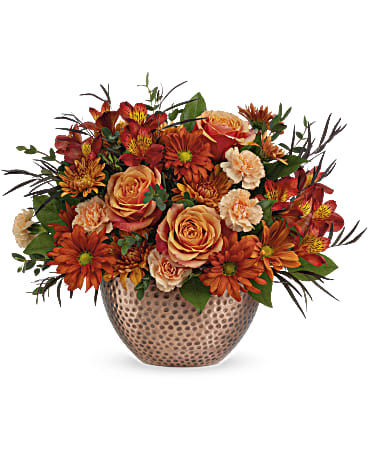 Copper Beauty Centerpiece - Capture the beauty of fall with the warm autumn hues of this lush rose bouquet, artfully arranged in a copper-finished keepsake bowl with timeless hammered detailing. Orange roses, red alstroemeria, miniature peach carnations and bronze cushion spray chrysanthemums are arranged with lemon leaf, parvifolia eucalyptus, and red agonis. Delivered in Teleflora's Copper Beauty bowl. Approximately 16 1/2" W x 13" H 