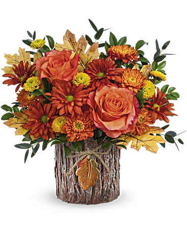 Woodsy Whisper Bouquet - These fabulous blooms are certain to captivate everyone, presented in a magnificent vase inspired by tree bark and adorned with a ceramic autumn leaf charm. Teleflora's Woodsy Whisper Bouquet features vibrant orange roses, yellow button spray chrysanthemums, bronze cushion spray chrysanthemums, bronze daisy spray chrysanthemums, parvifolia eucalyptus, and huckleberry accents. Presented in Teleflora's Enchanted Forest Cylinder, it embodies natural beauty and rustic charm for autumn. Approximately 12 1/2" W x 12 1/2" H