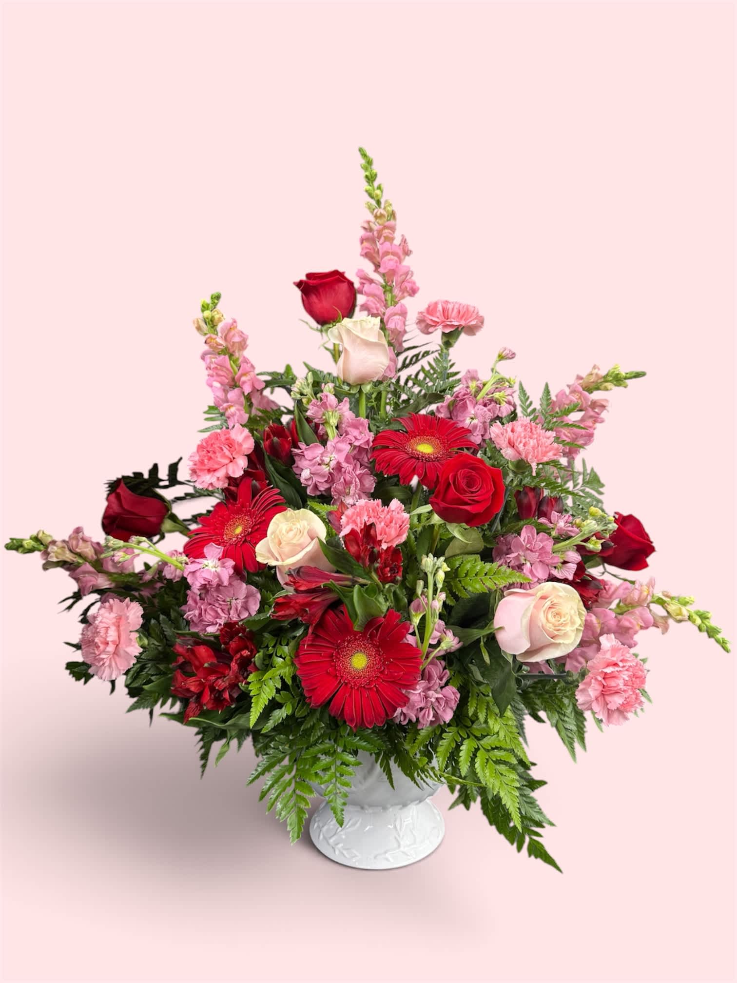 Mixed pink and red flower arrangement in a white vase