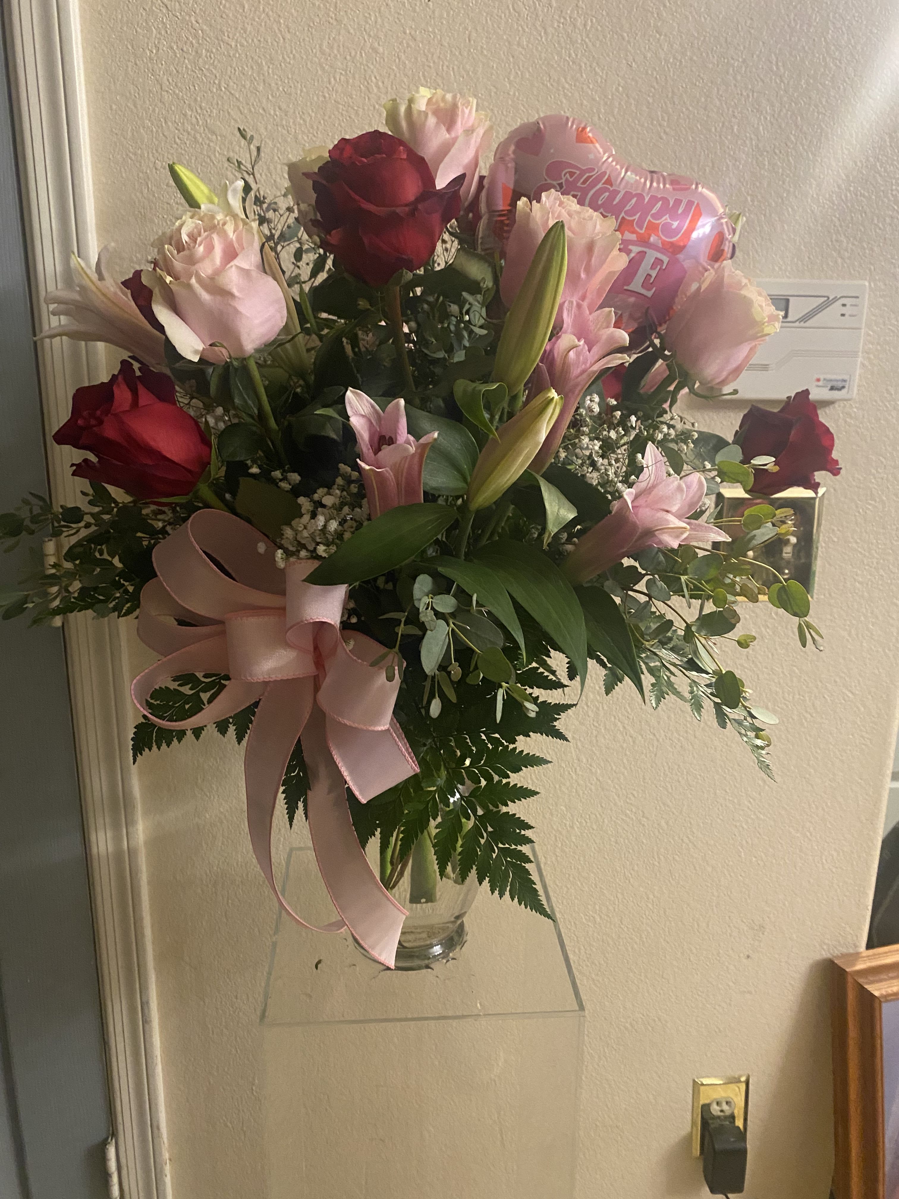 Bouquet of pink and red roses with lilies in a glass vase