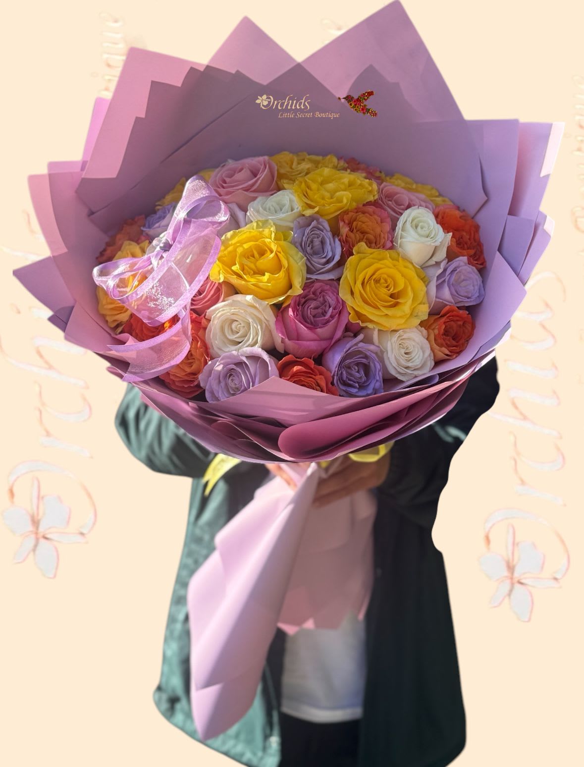 Bouquet of multicolored roses wrapped in purple paper with a pink ribbon