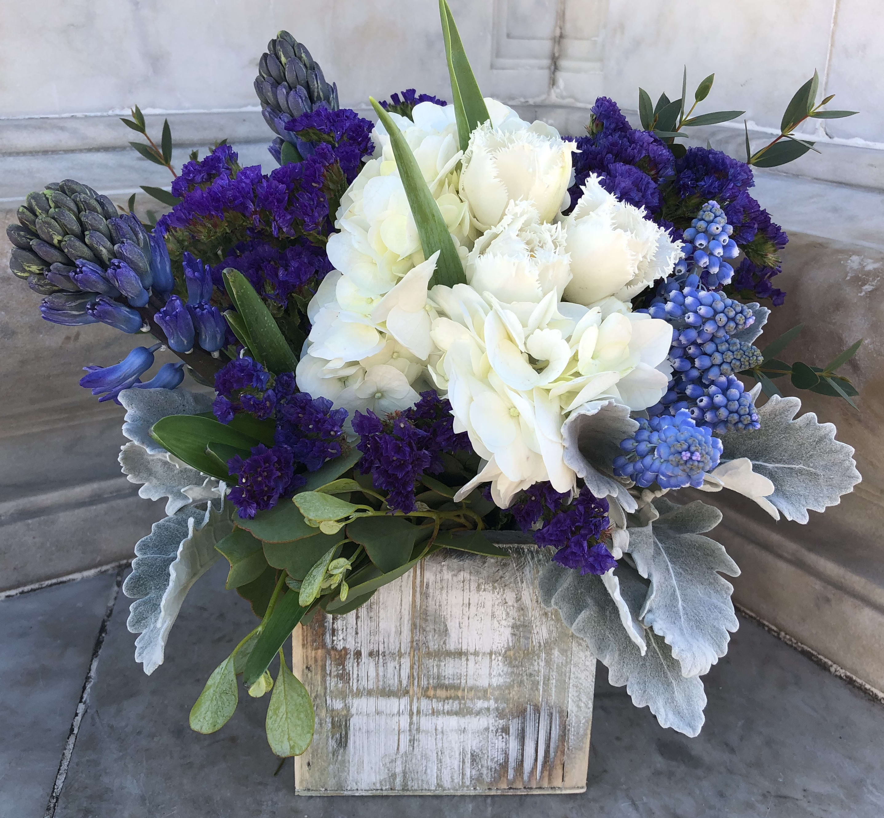 White and purple floral arrangement in a rustic wooden box