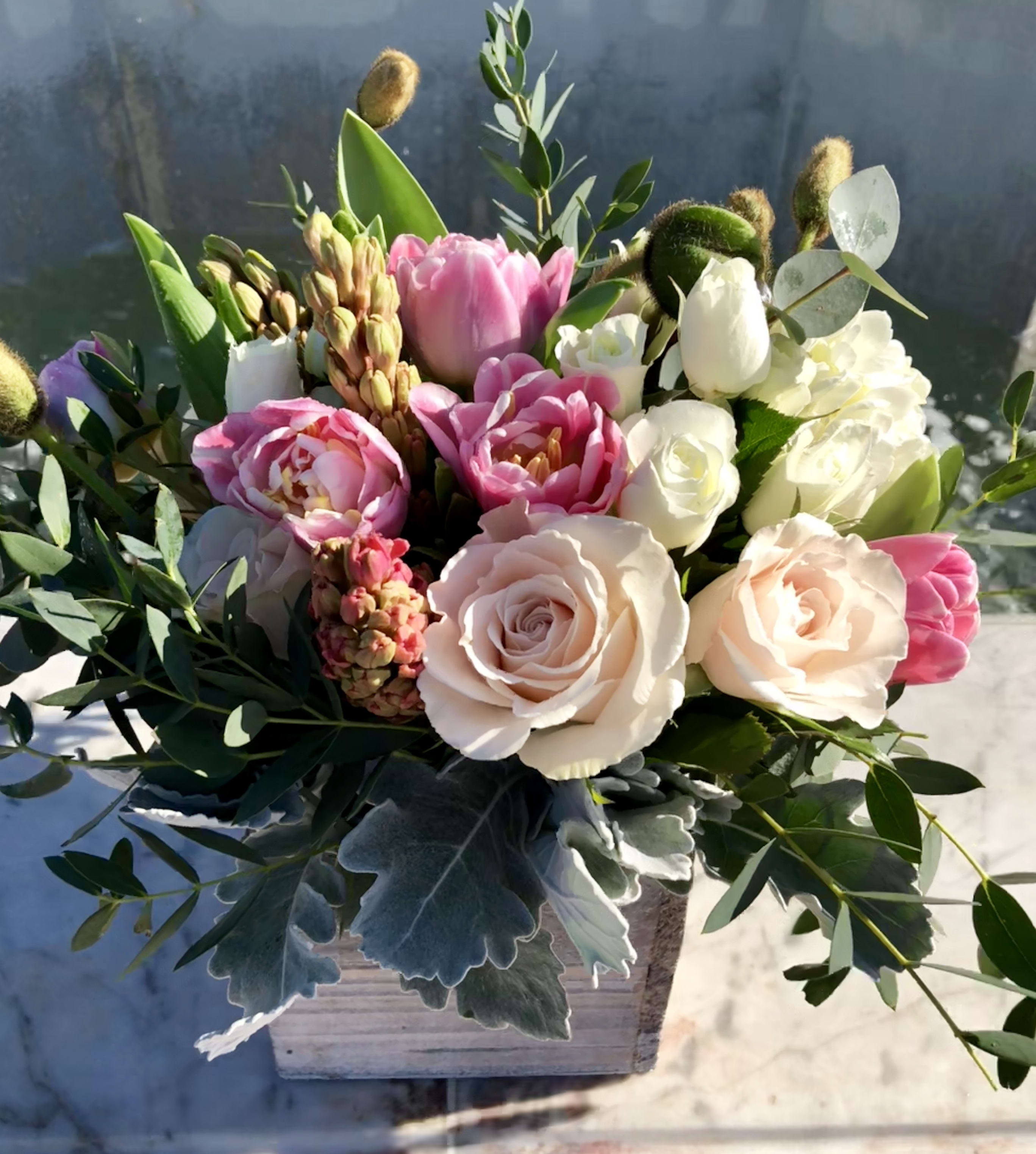 Low arrangement of blush roses and pink tulips in a whitewashed wooden box