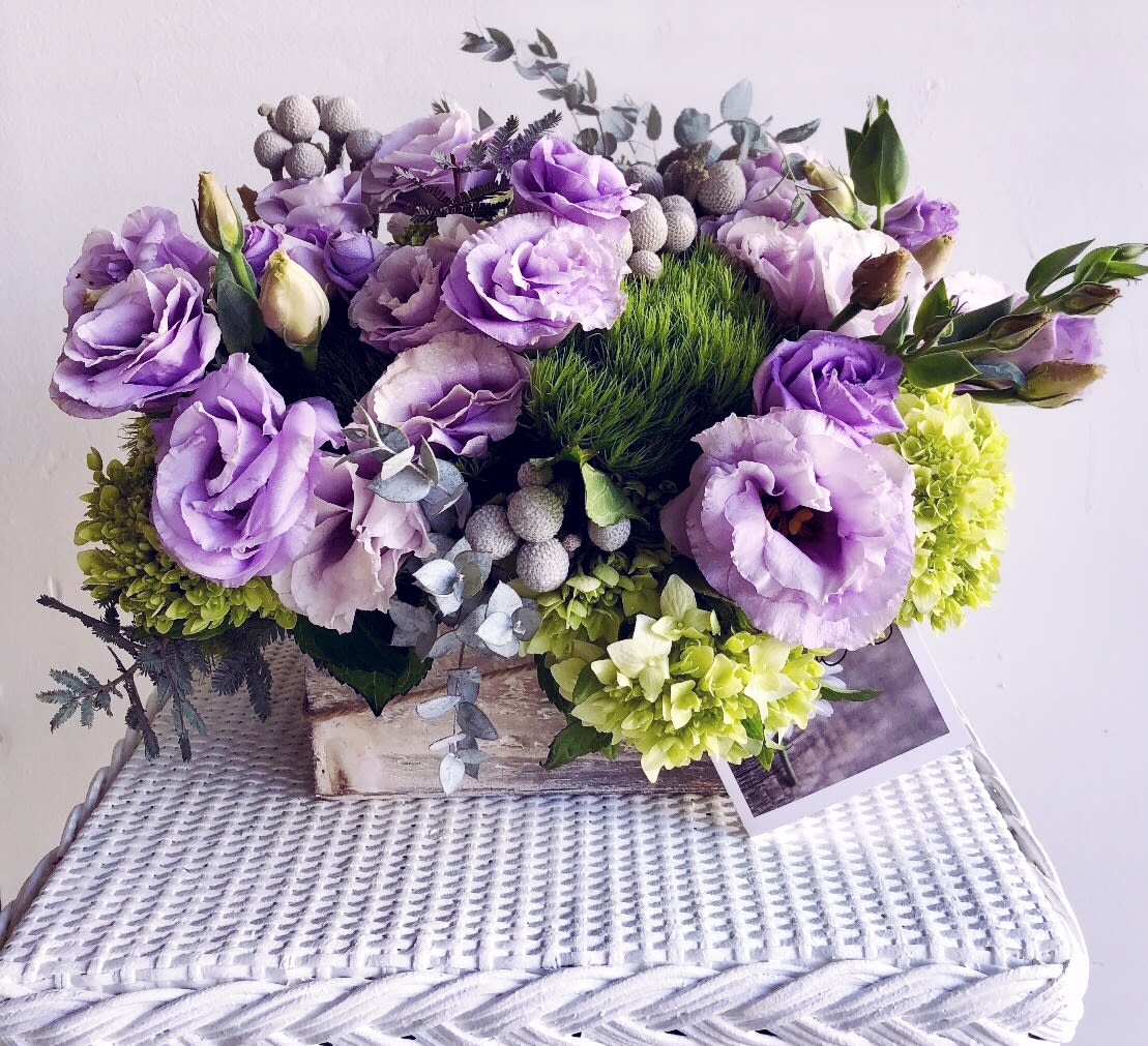 Purple lisianthus and green hydrangeas arranged in a low basket