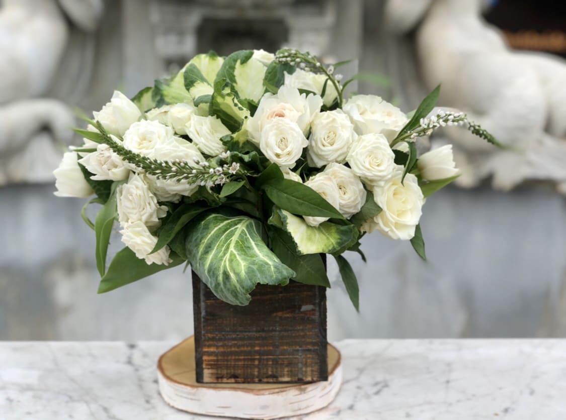 White rose bouquet in a rustic wooden box with green foliage
