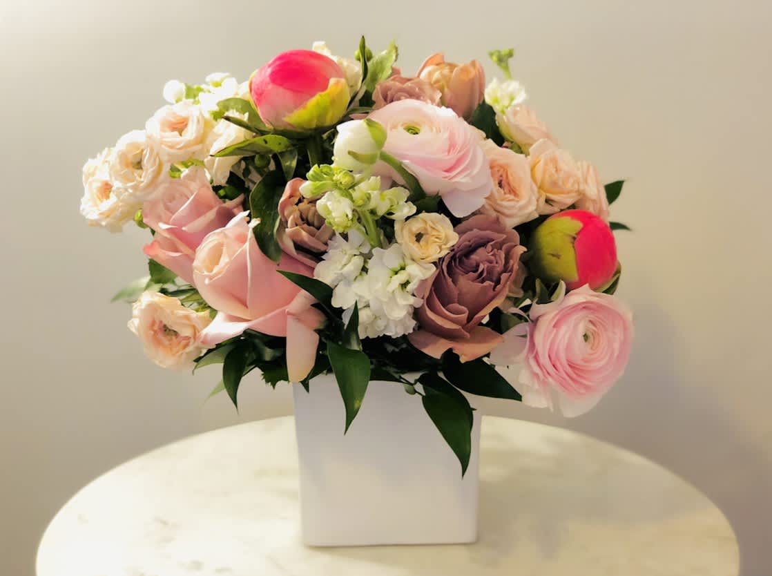 Pink and peach mixed bouquet in a white square vase