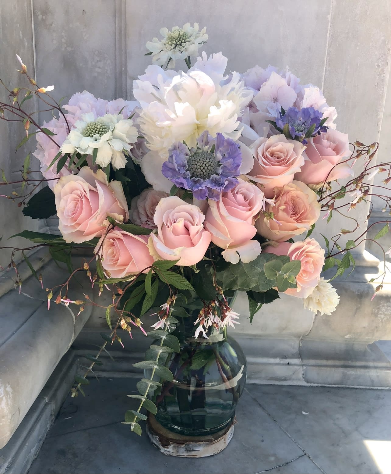 Pink roses and pastel blooms arranged in a glass vase